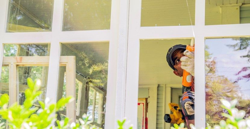 A man is working on a window with a drill.