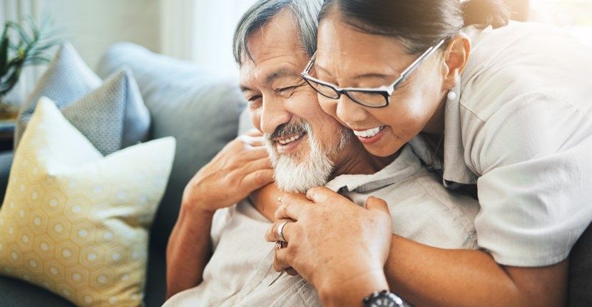 A woman is hugging an older man on a couch.