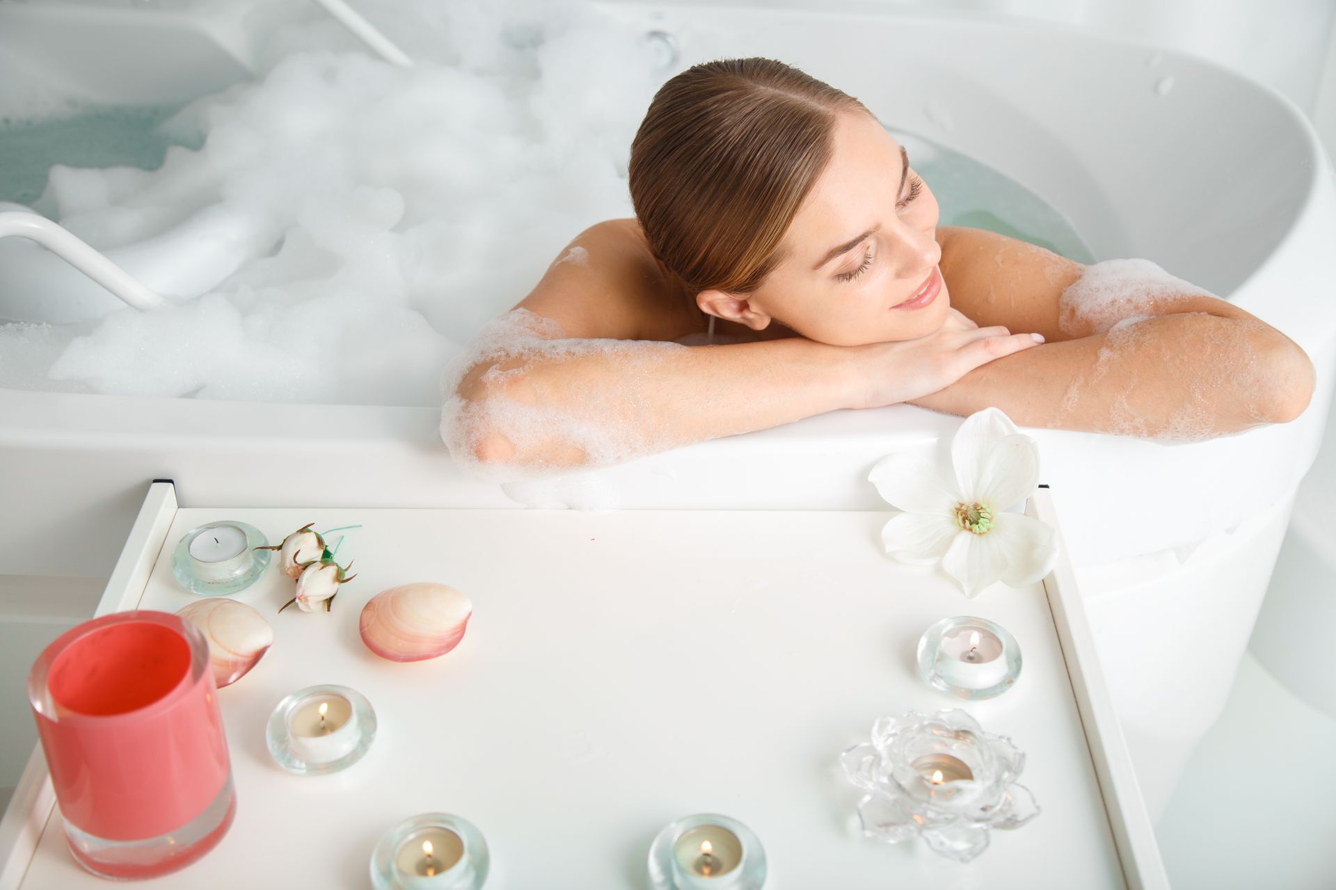 a woman is taking a bath in a bathtub with a cup of coffee .