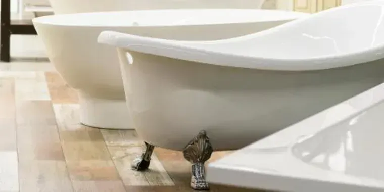 a row of white bathtubs are sitting on a wooden floor in a bathroom .