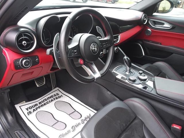 Interior of a red and black Alfa Romeo car, showing steering wheel, dashboard, and seats.