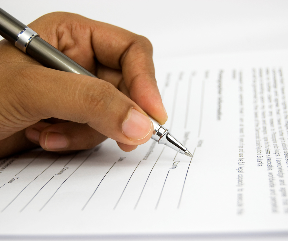 photo of person holding a pen and filling out a form