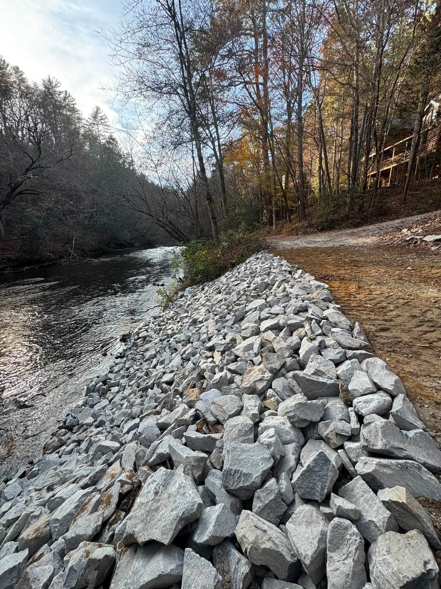 Rock-lined streambed beside leafless trees in a wooded area