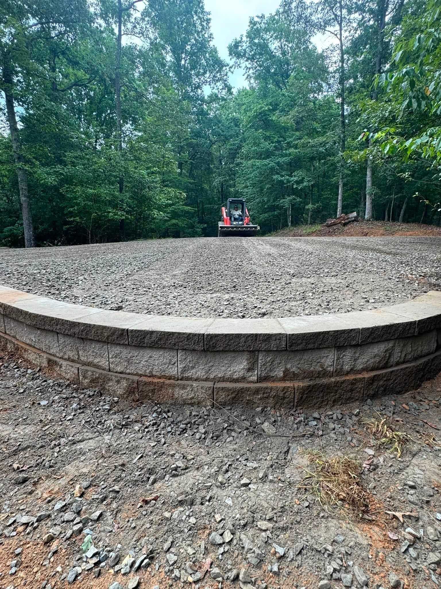 Curved stone amphitheater seating in a wooded outdoor park, with a small stage in the center.