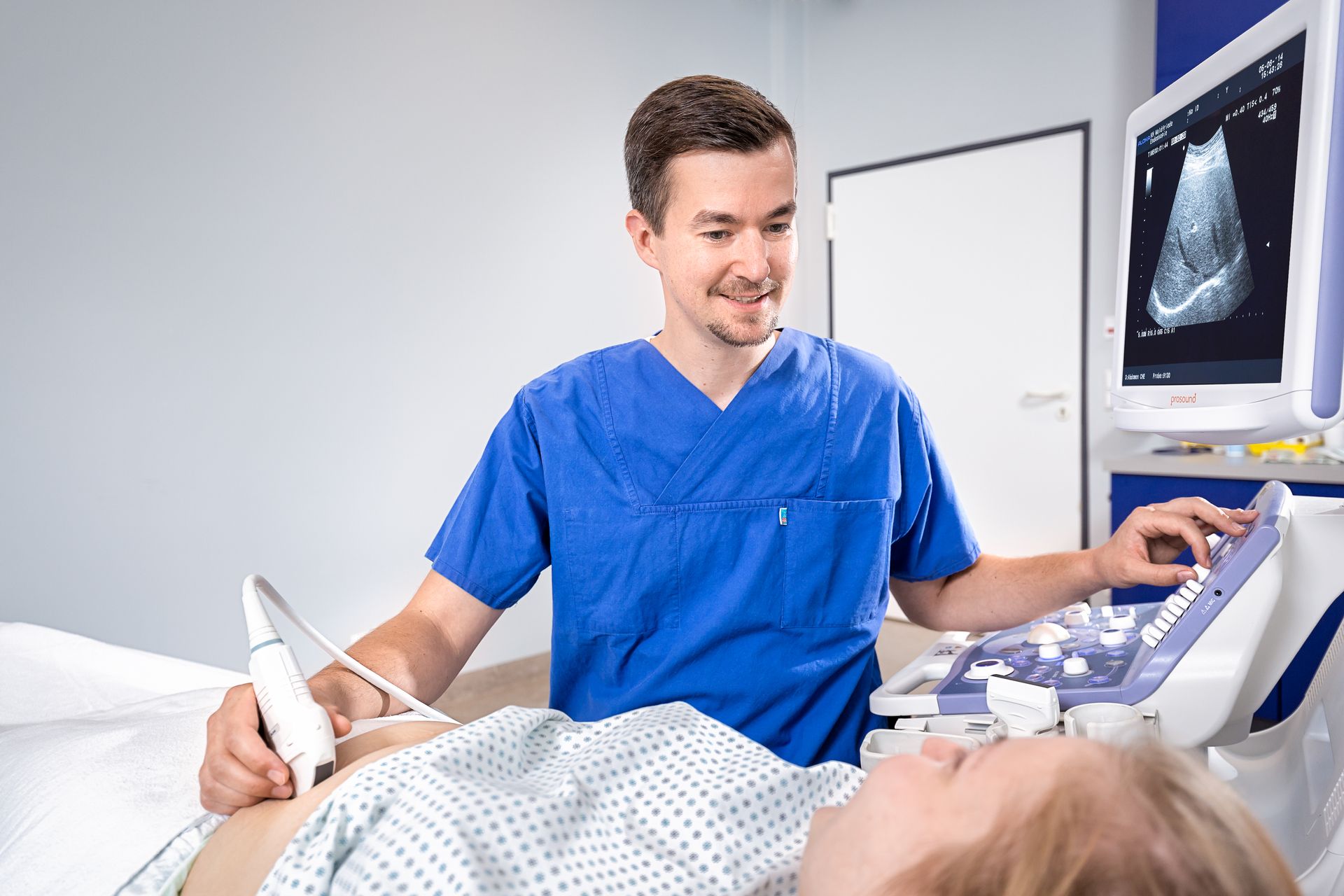 Ein Arzt untersucht den Bauch einer schwangeren Frau mit einem Ultraschallgerät.