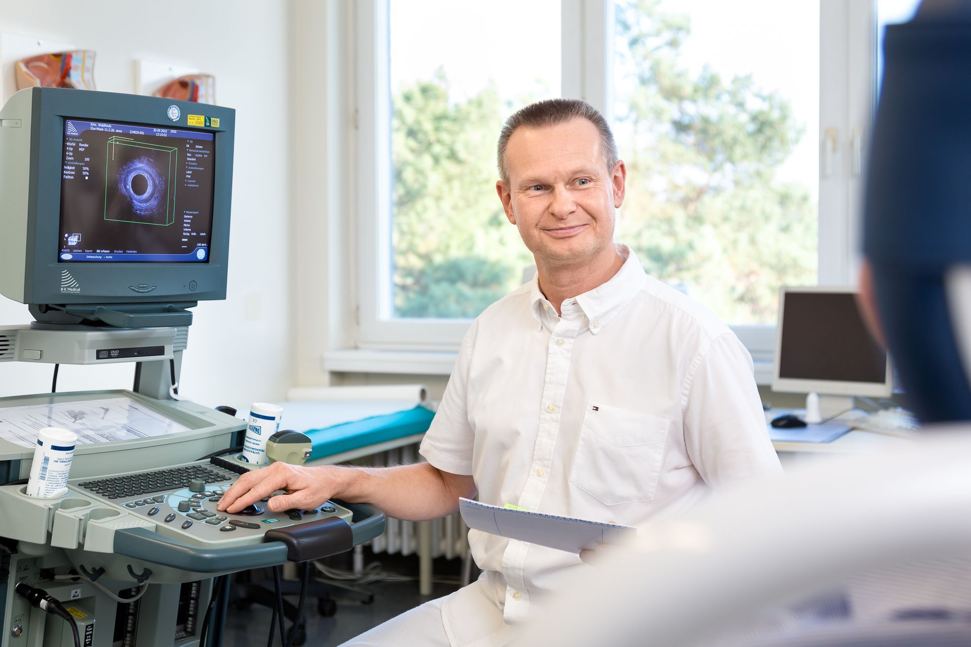 Ein Mann sitzt vor einem Ultraschallgerät.