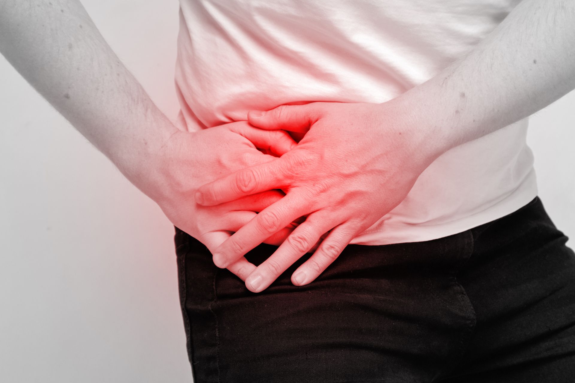 Eine Frau hält sich mit den Händen den schmerzenden Bauch