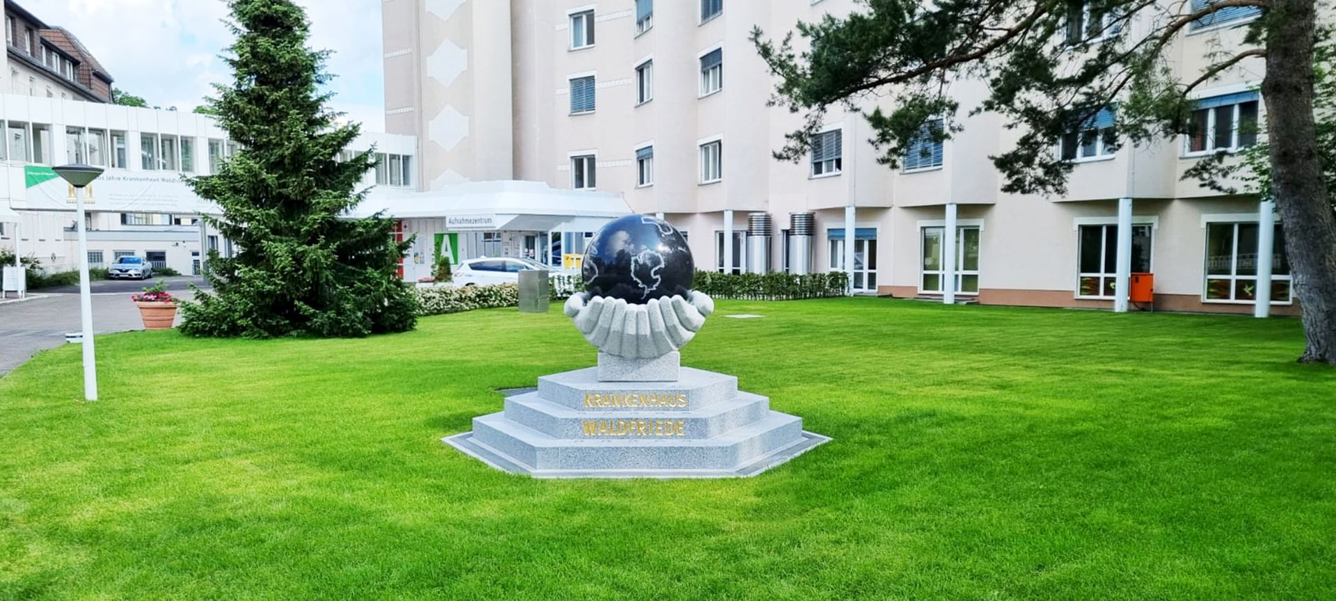 Eine Globusstatue in einer Vase in einem Park vor einem Gebäude.