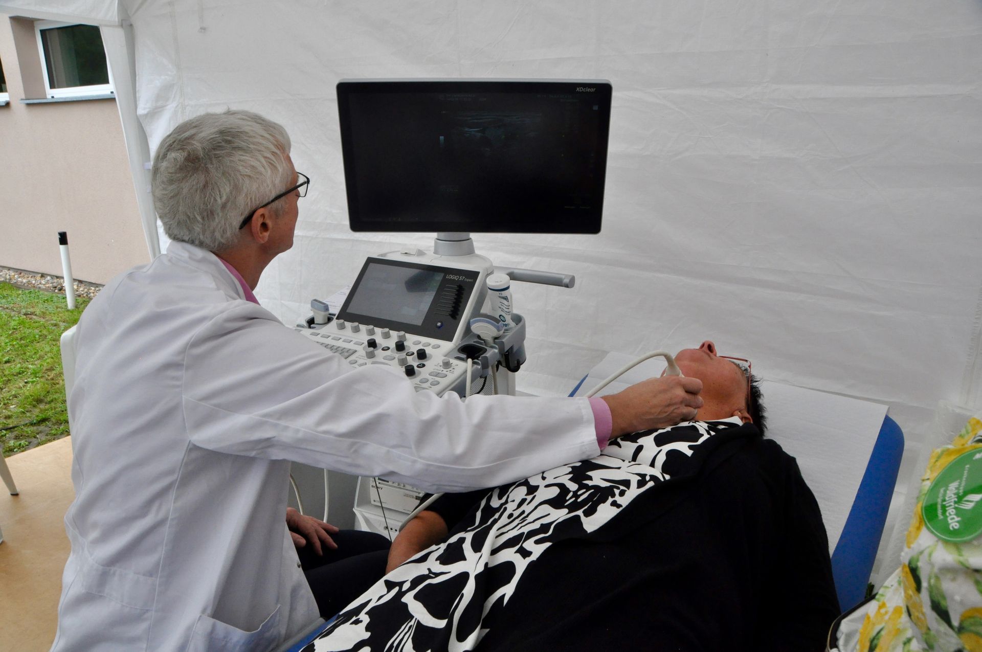 Ein Arzt untersucht den Hals eines Patienten mit einem Ultraschallgerät.