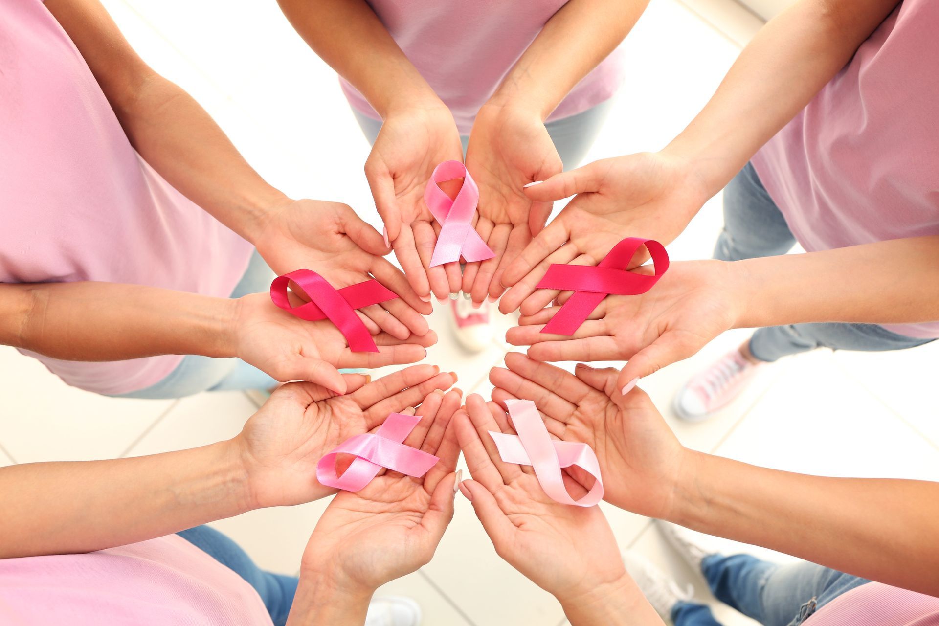 Eine Gruppe von Menschen hält einen Kreis aus rosa Bändern in den Händen.