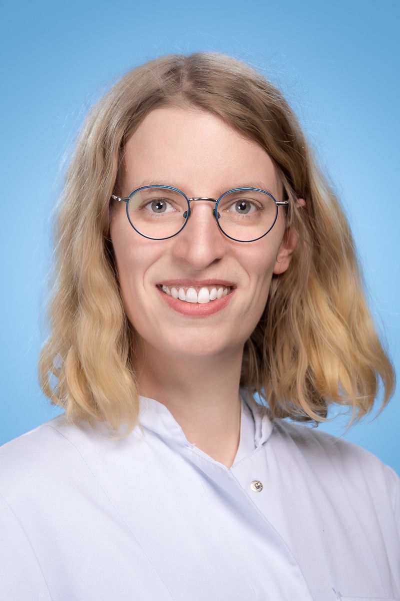 Eine Frau mit Brille und weißem Hemd lächelt in die Kamera.