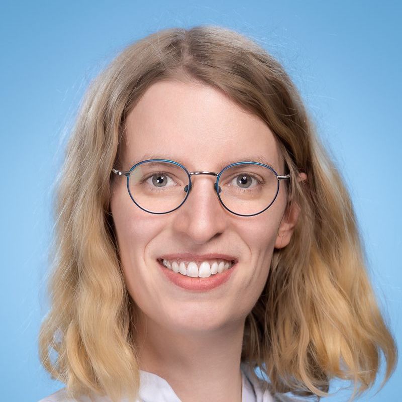 Die Frau trägt eine Brille und lächelt in die Kamera.