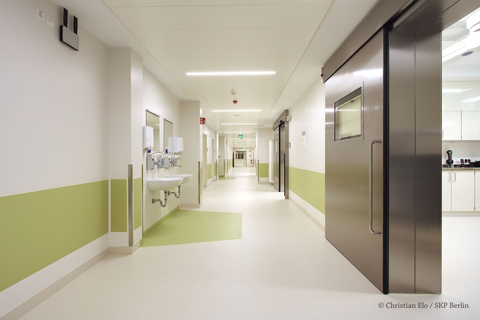 Ein Krankenhausflur mit Waschbecken und Schiebetür