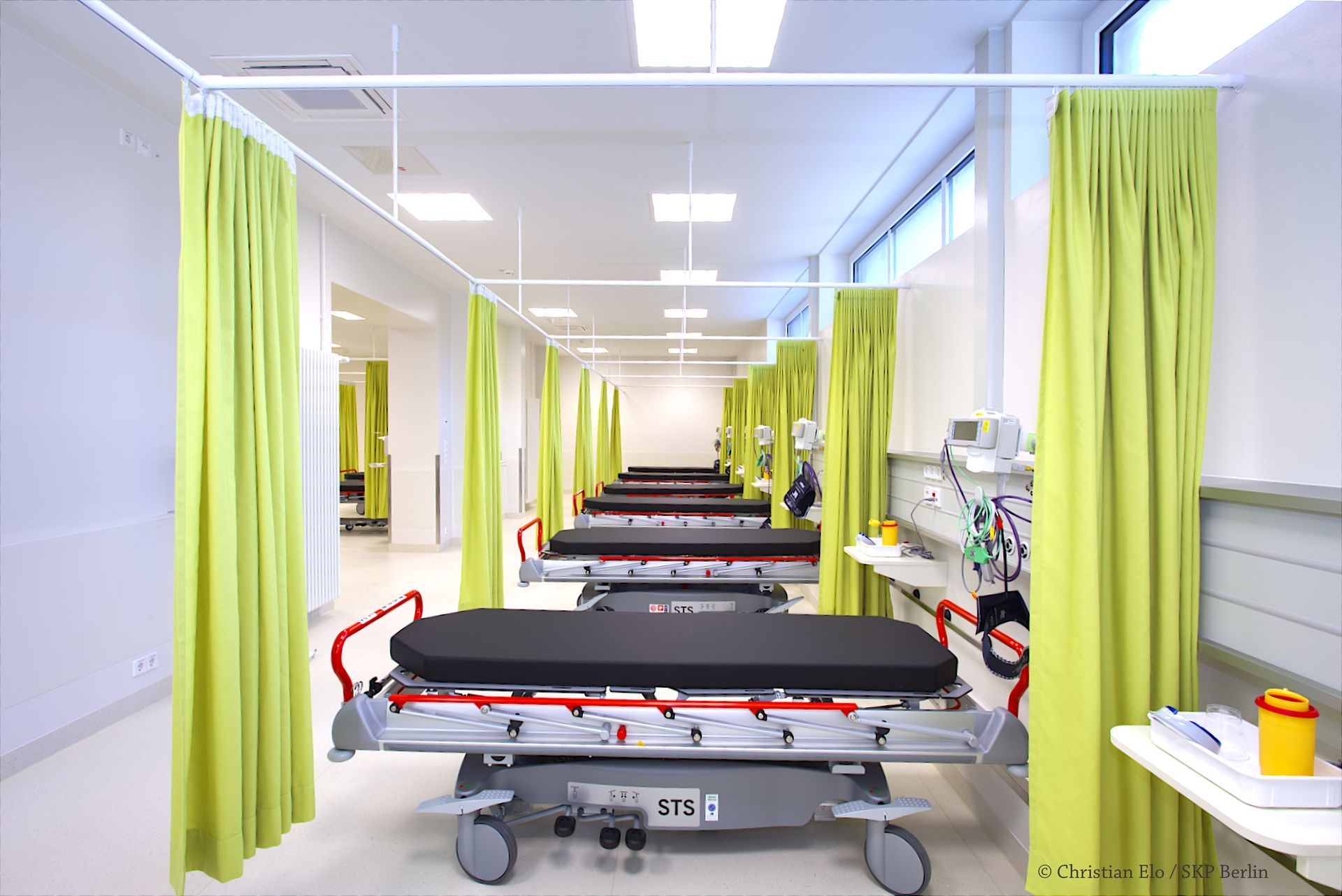 Eine Reihe von Tragen in einem Krankenhauszimmer mit grünen Vorhängen.
