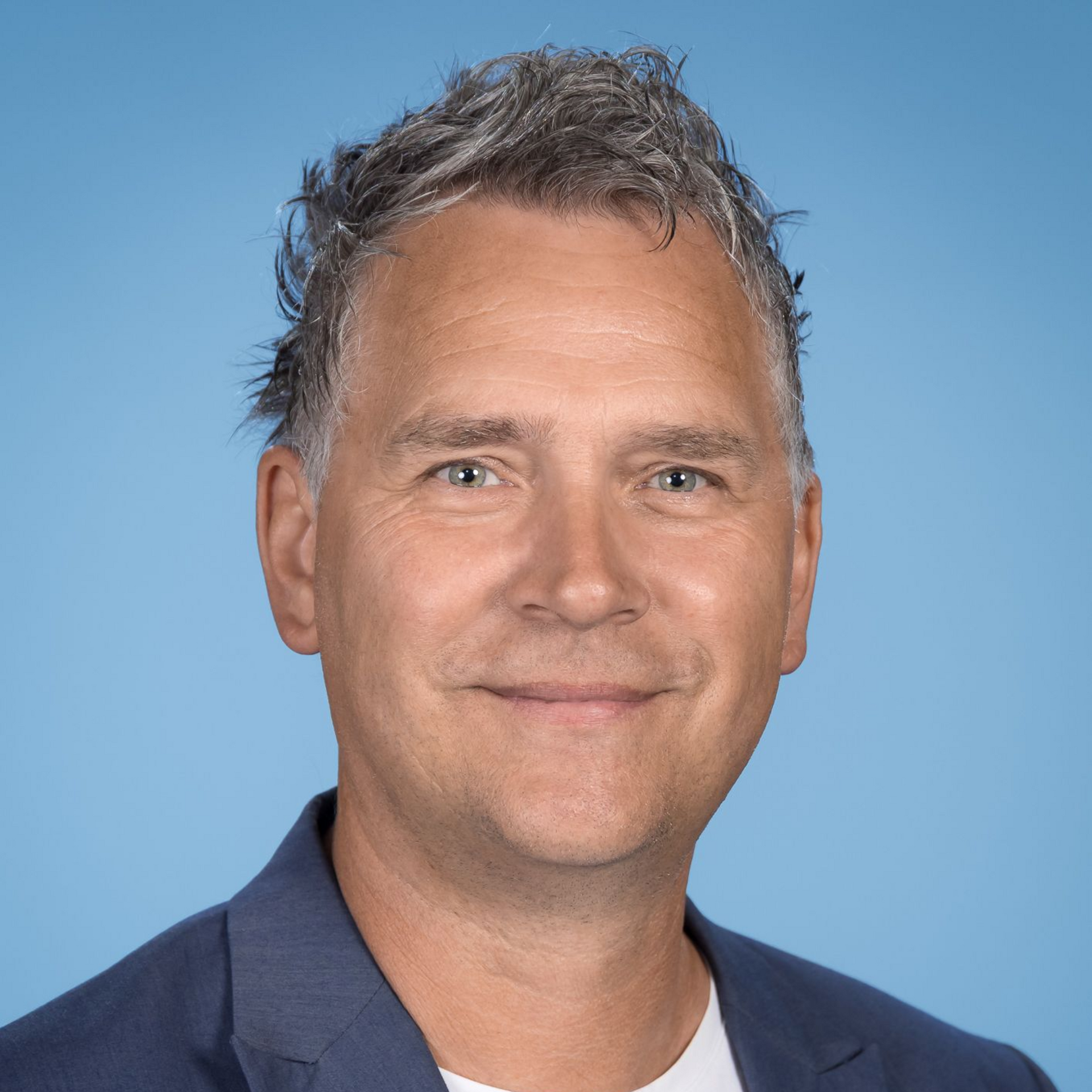 Ein Mann mit Brille und Schnurrbart trägt Anzug und Krawatte.