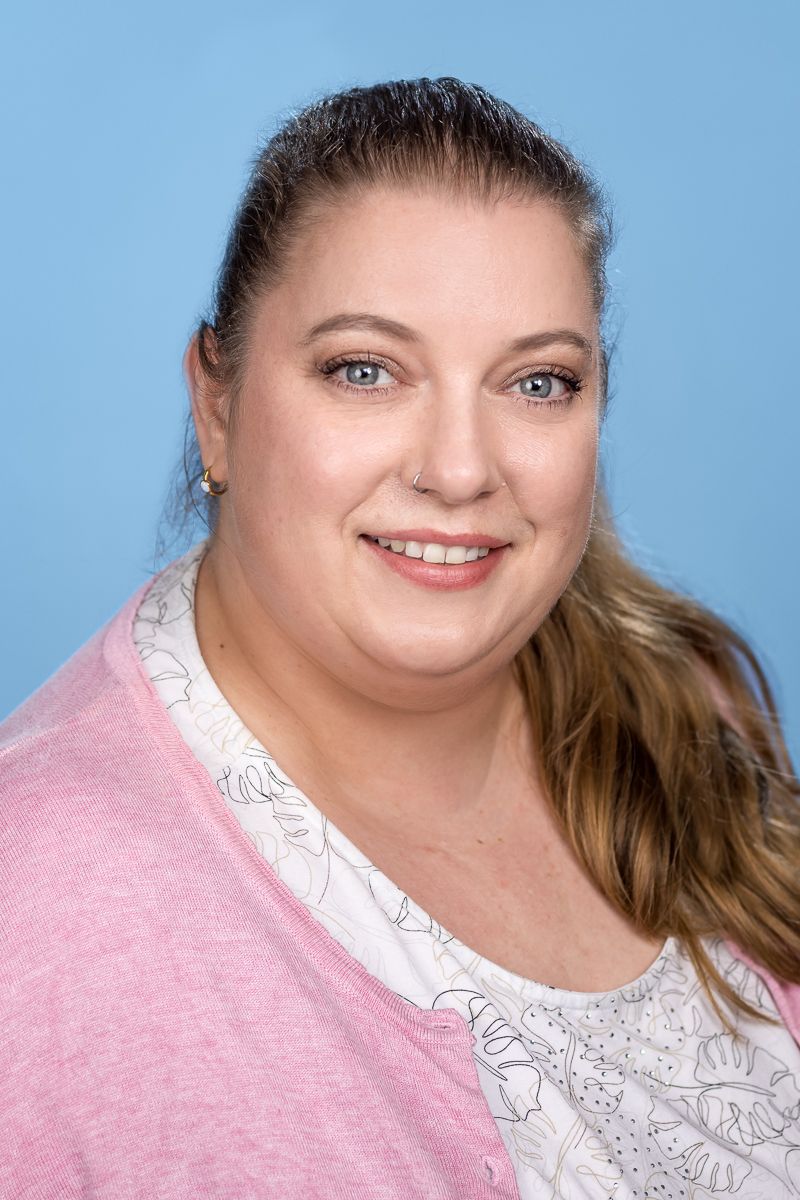 Eine Frau mit Brille und Halskette lächelt in die Kamera.