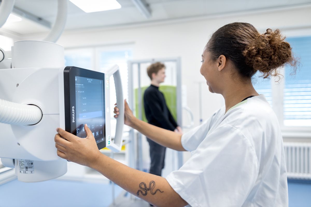 Eine Krankenschwester stellt in einem Krankenhauszimmer einen Monitor ein.