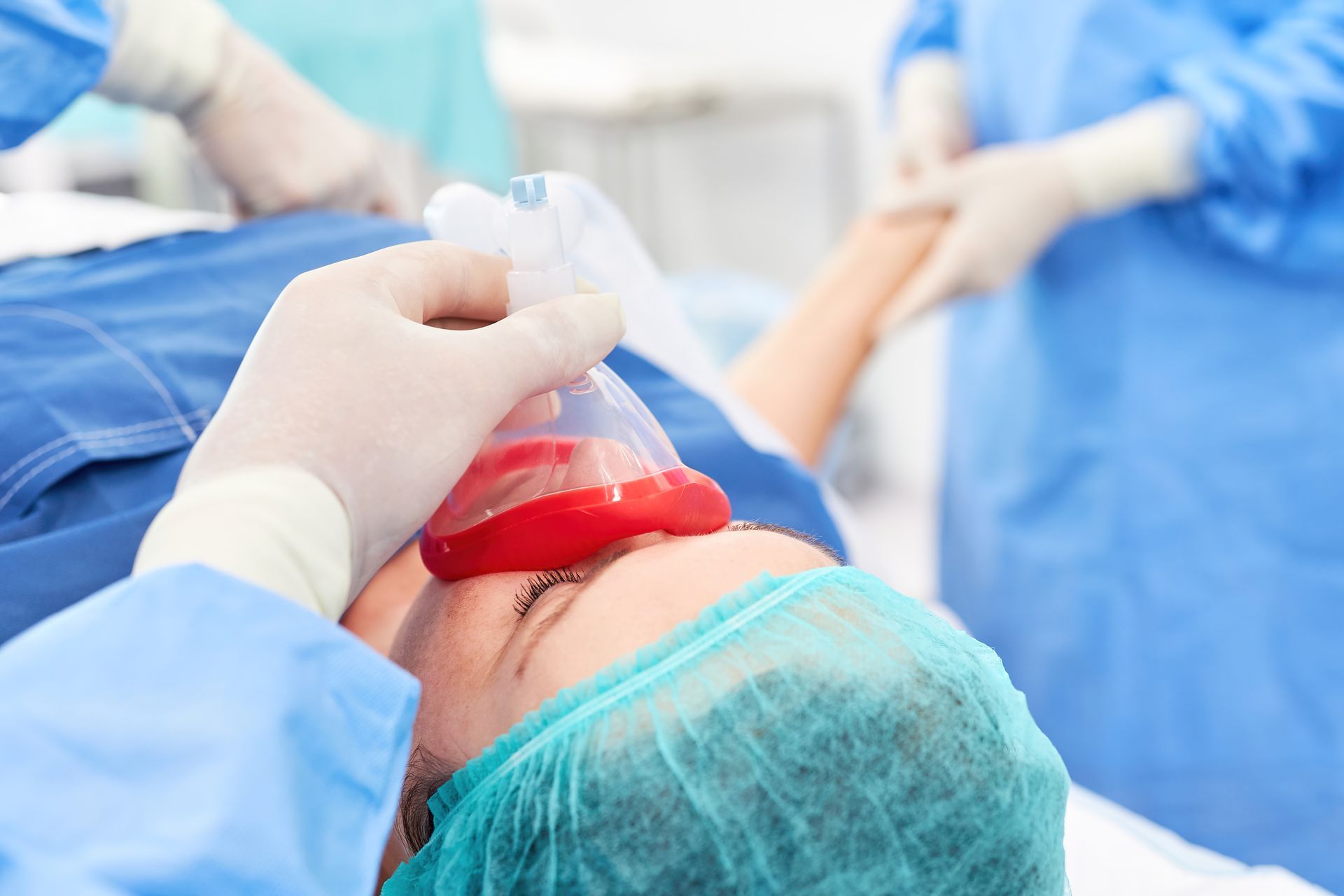 Ein Chirurg setzt einem Patienten eine Narkosemaske auf.