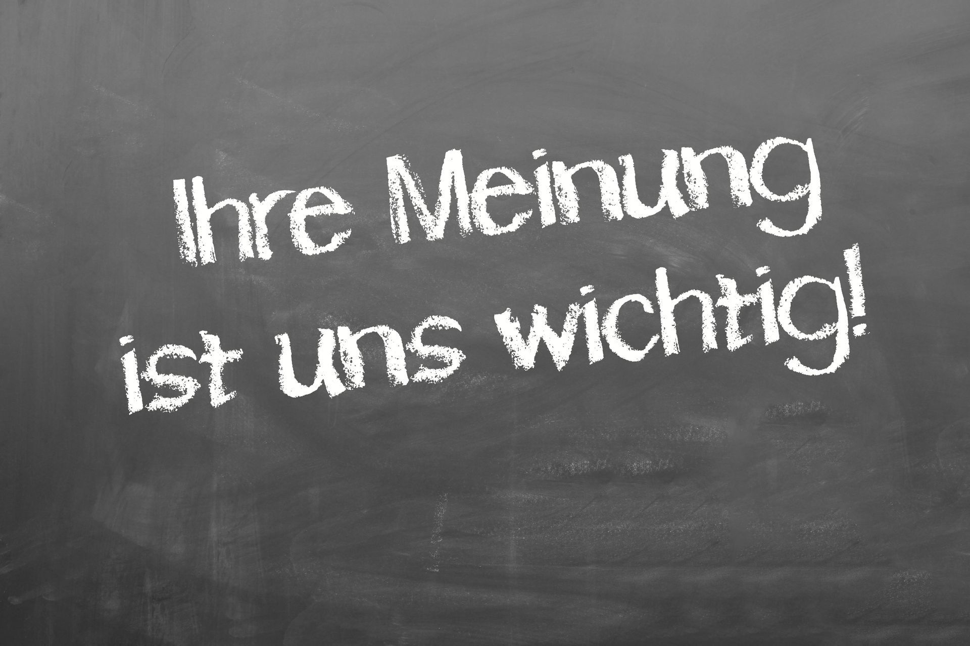 A blackboard with the words ihre meinung ist uns wichtig written in white chalk