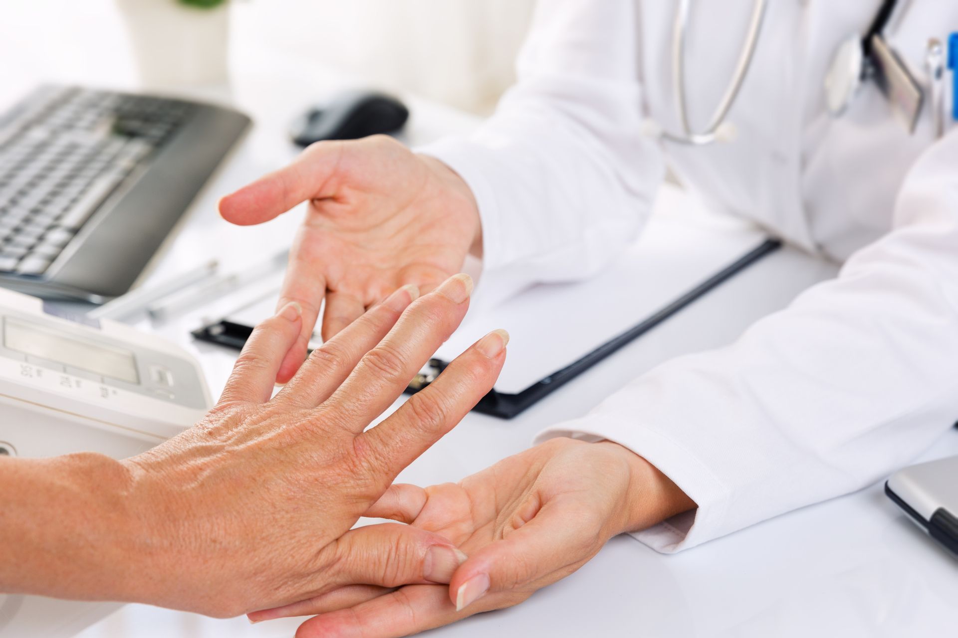 Ein Arzt untersucht die Hand eines Patienten mit einem Stethoskop.