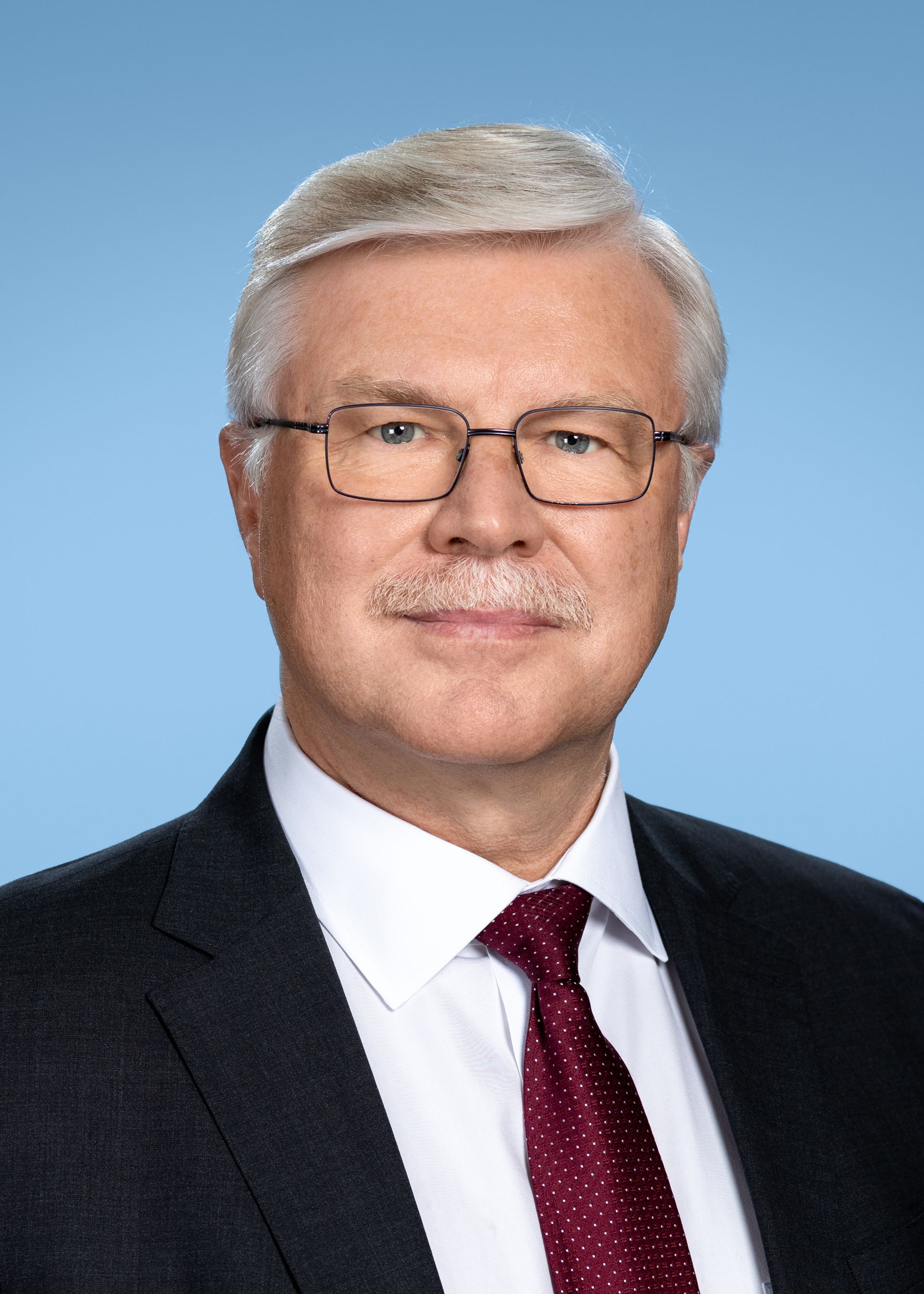 Ein Mann in Anzug und Krawatte mit Brille und Schnurrbart