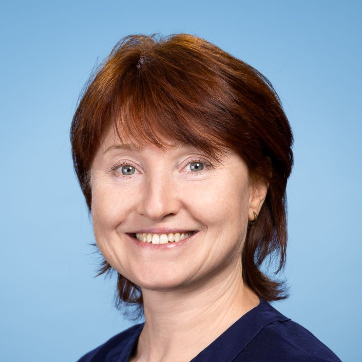 Eine Nahaufnahme des Gesichts einer Frau vor blauem Hintergrund.