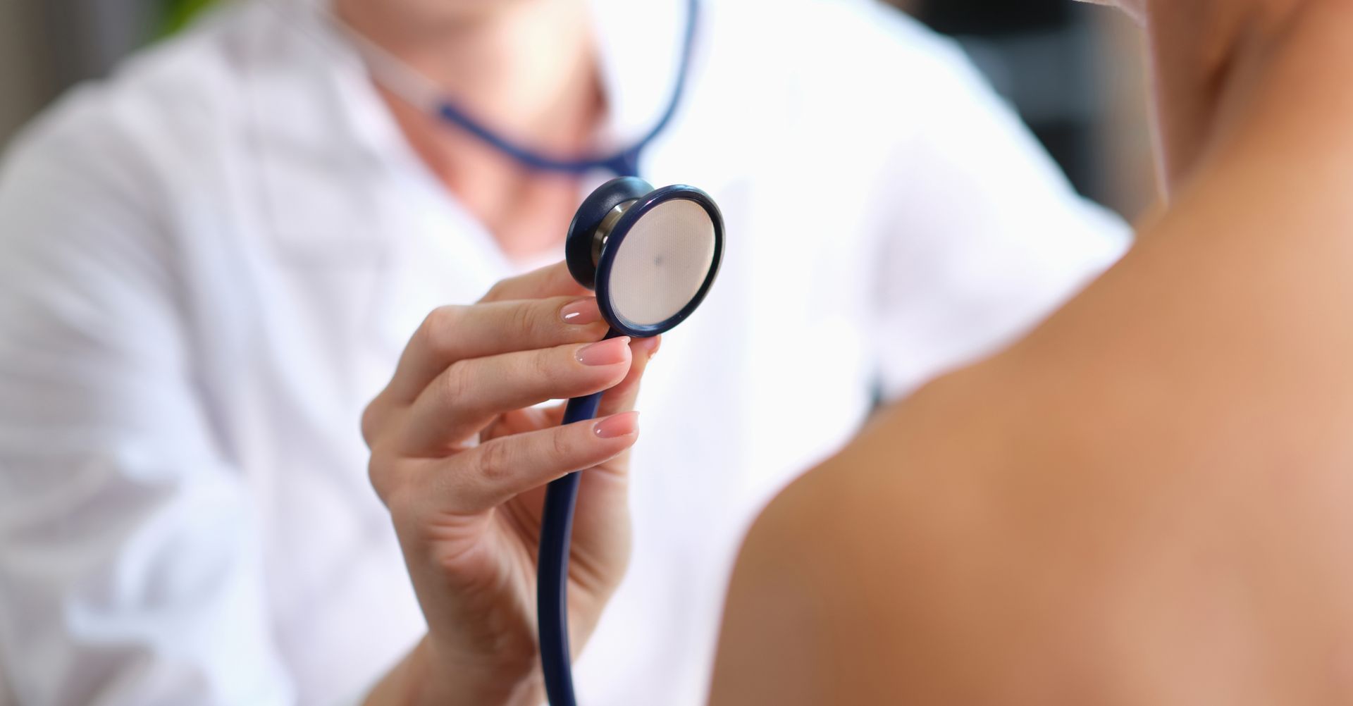 Ein Arzt hört mit einem Stethoskop den Herzschlag eines Patienten ab.