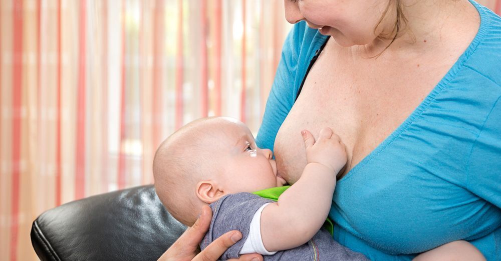 Eine Frau stillt ihr Baby auf einem Sofa.