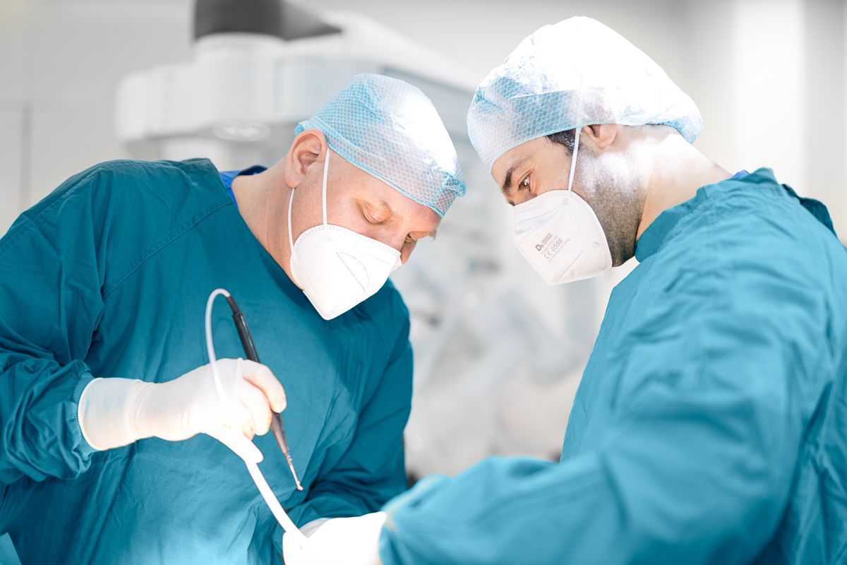 Zwei Chirurgen operieren einen Patienten in einem Operationssaal.
