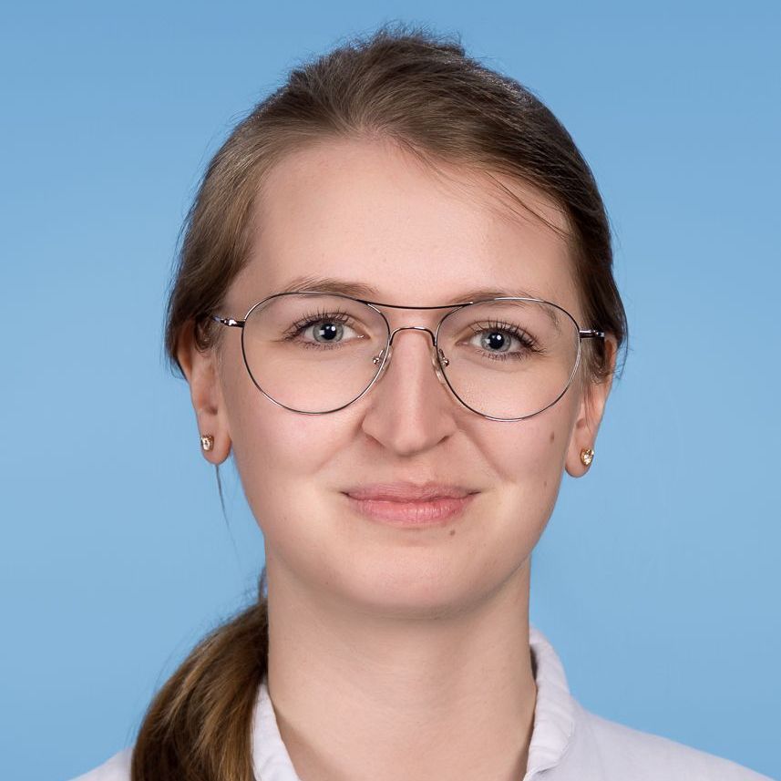 Frau mit Brille, heller Haut, lächelnd, vor blauem Hintergrund.