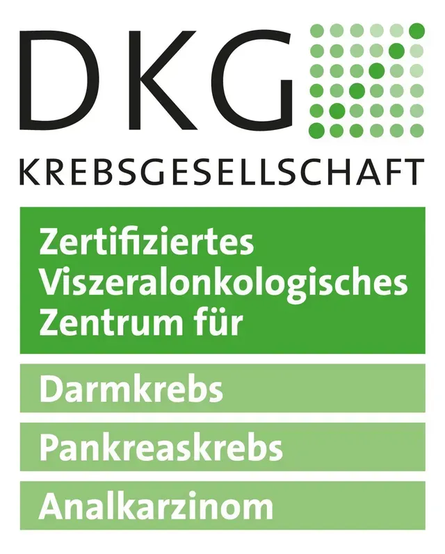 Ein kahlköpfiger Mann in weißem Kittel und Krawatte lächelt in die Kamera.