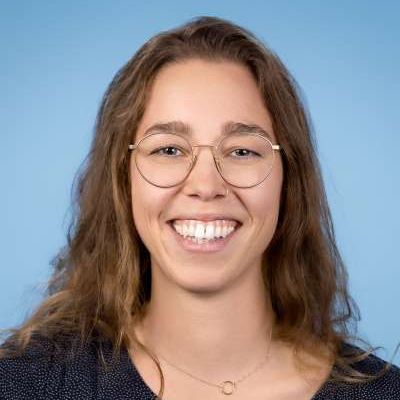 Eine Frau mit Brille und Halskette lächelt in die Kamera.