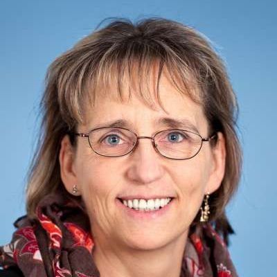 Eine Frau mit Brille und Schal lächelt in die Kamera.