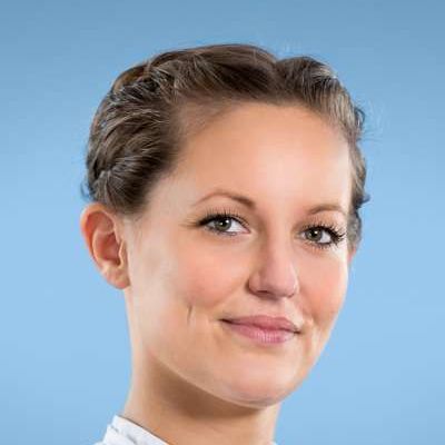 Eine Frau in einem weißen Hemd lächelt in die Kamera.