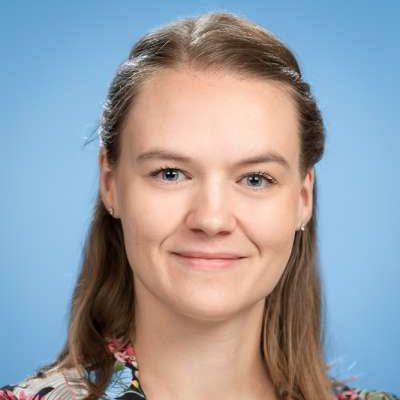 Eine Nahaufnahme des Gesichts einer Frau vor blauem Hintergrund.