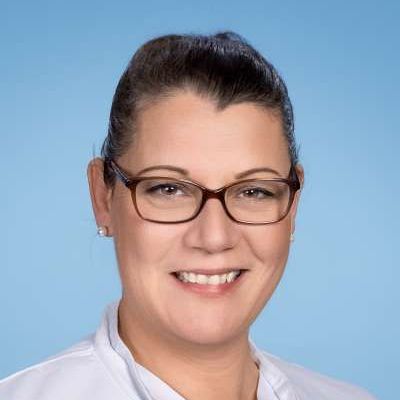 Eine Frau mit Brille und weißem Hemd lächelt in die Kamera.