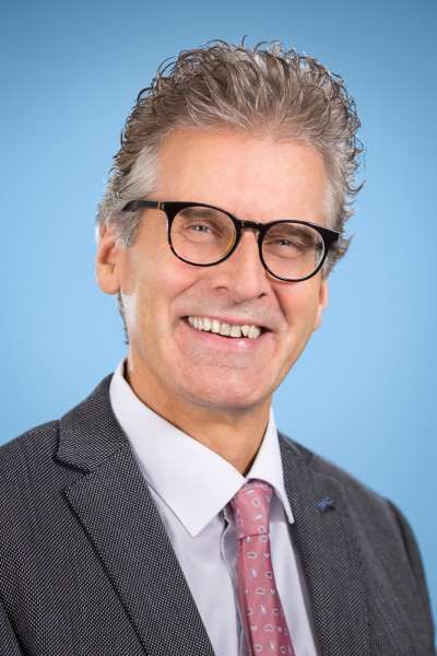 Ein Mann in Anzug und Krawatte lächelt in die Kamera.