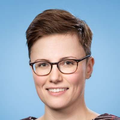Die Frau trägt eine Brille und lächelt in die Kamera.