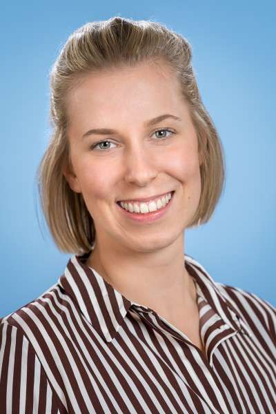 Eine Frau in einem gestreiften Hemd lächelt in die Kamera.