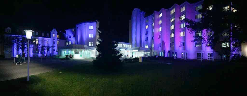 Ein großes Gebäude wird nachts mit violetten Lichtern beleuchtet.