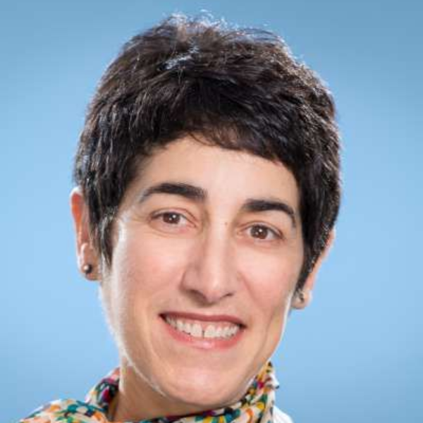 Eine Frau mit einem Schal um den Hals lächelt in die Kamera.