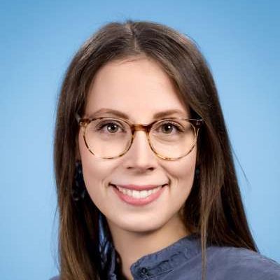 Die Frau trägt eine Brille und lächelt in die Kamera.