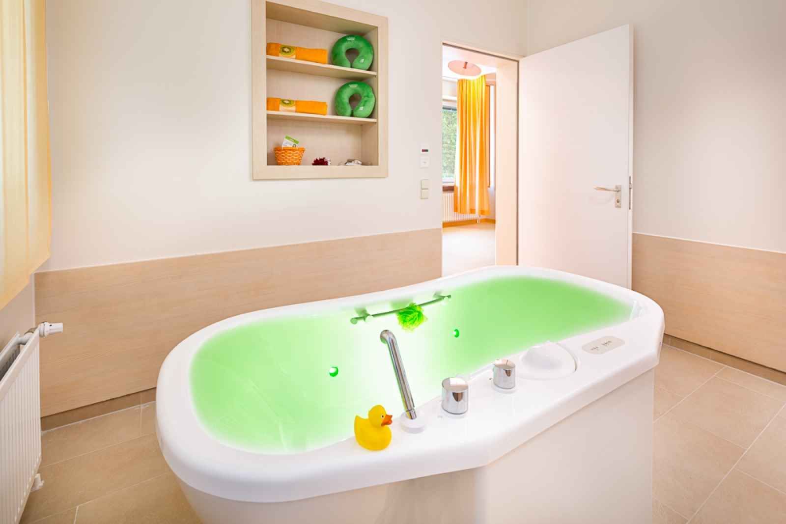 Eine Badewanne mit grünem Wasser und gelben Gummienten darin