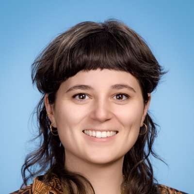 Eine Nahaufnahme des Gesichts einer lächelnden Frau vor blauem Hintergrund.