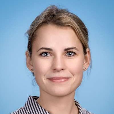 Eine Nahaufnahme des Gesichts einer lächelnden Frau, die ein gestreiftes Hemd trägt.