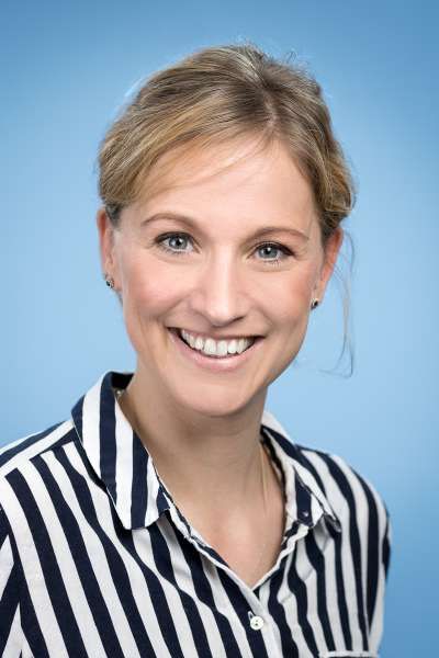 Eine Frau in einem gestreiften Hemd lächelt in die Kamera.
