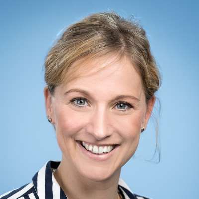 Eine Frau in einer gestreiften Jacke lächelt in die Kamera.