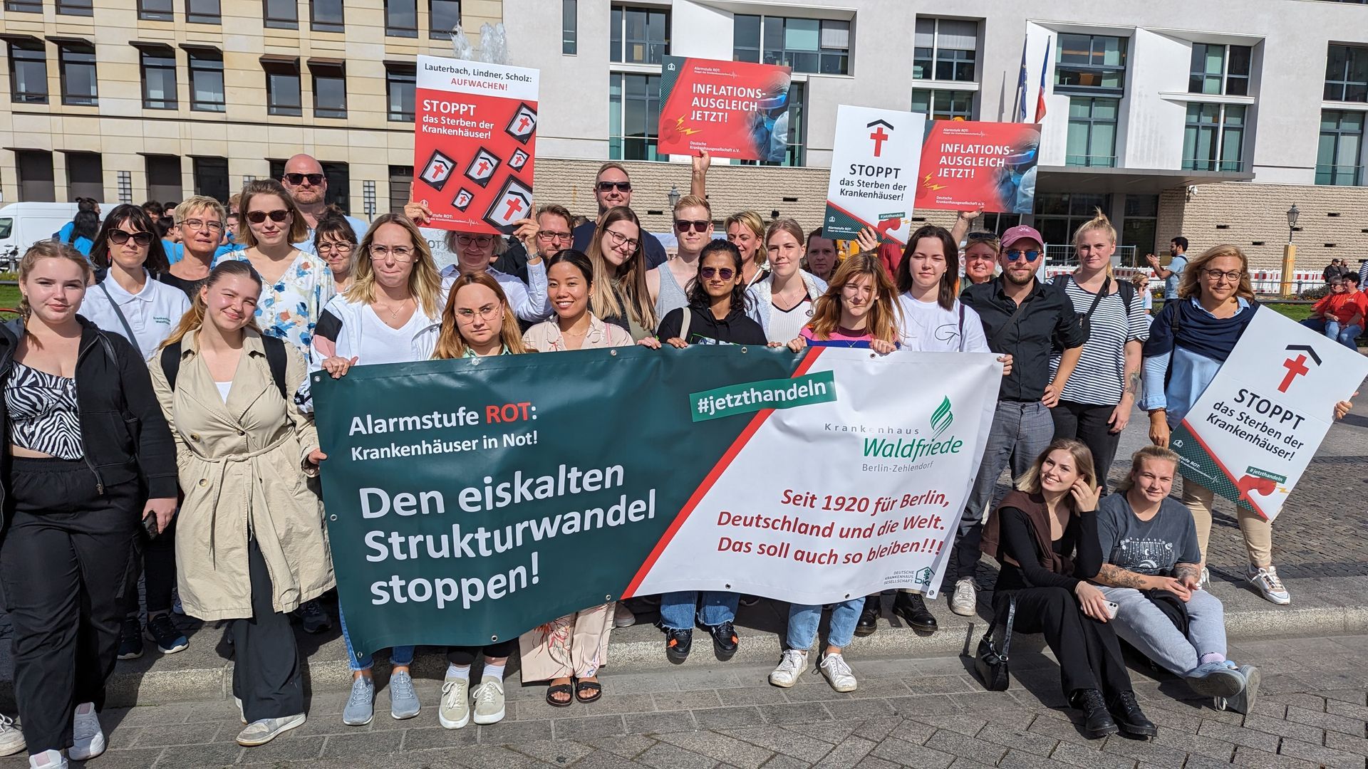 Eine Gruppe von Menschen steht mit Schildern vor einem Gebäude.