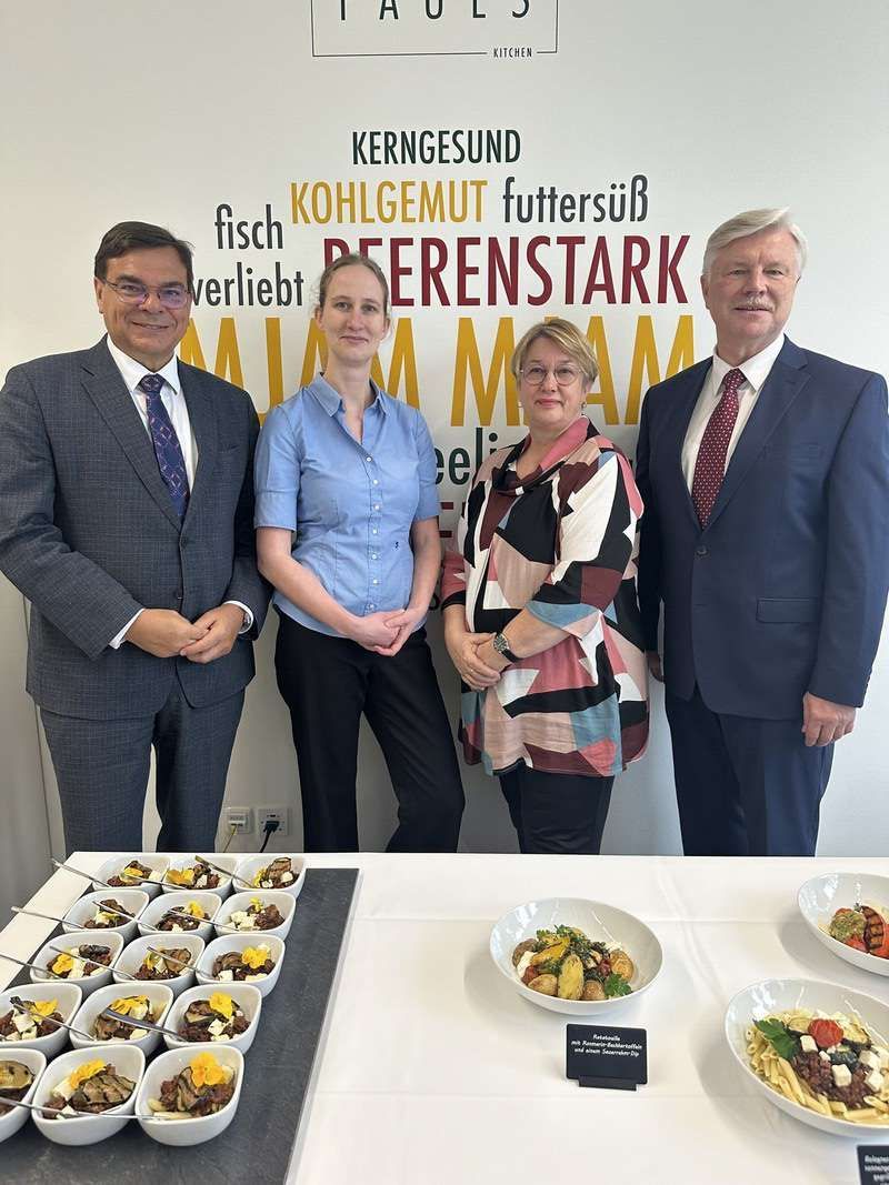 Eine Gruppe von Menschen steht vor einer Wand mit der Aufschrift „kerngesund“