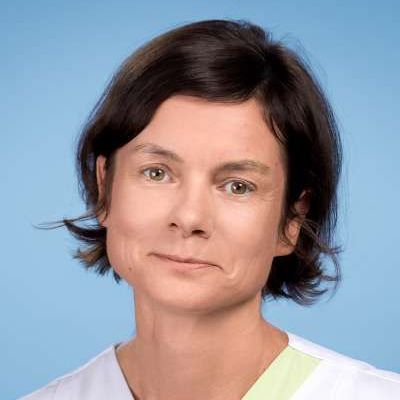 Eine Nahaufnahme des Gesichts einer Frau vor blauem Hintergrund.